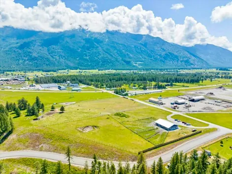 Aerial view of the Glacier Adventure Field and blue ranch building, with the Flathead Valley mountains beyond.